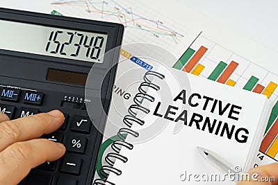 On the table there is a calculator, reports with graphs and a notepad with the inscription - ACTIVE LEARNING Stock Photo