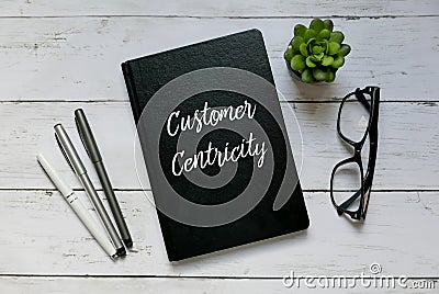 Business concept. Top view of glasses,plant,pen and notebook written with Customer Centricity. Stock Photo