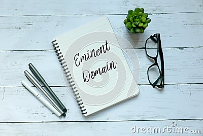 Business concept. Top view of pen,glasses,plant and notebook written with Eminent Domain. Stock Photo