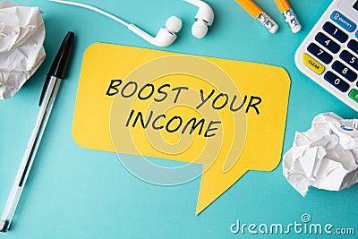 Business concept. Yellow speech bubble with Boost ypur income inscription, blue backgroud and office accesories - earphones, Stock Photo
