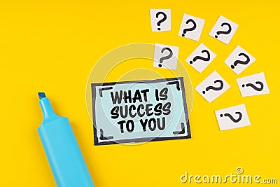 On the yellow surface is a marker, question marks and a sticker with the inscription - WHAT IS SUCCESS TO YOU Stock Photo