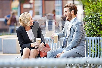 Business Couple On Park Bench With Coffee Stock Photo