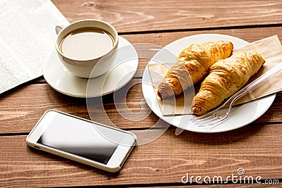 Business cup of coffee with croisant and phone on desk Stock Photo