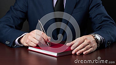 business disappointment concept. businessman in formal wear sitting at the desk and holds silver pen at his arm Stock Photo