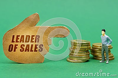 On the green surface of the coin, a figure of a man and a pointer - a hand with the inscription - LEADER OF SALES Stock Photo