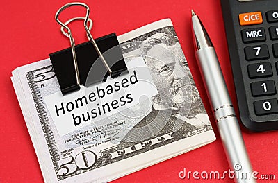 On a red surface lies a calculator, a pen, dollars and paper with the inscription - Homebased business Stock Photo