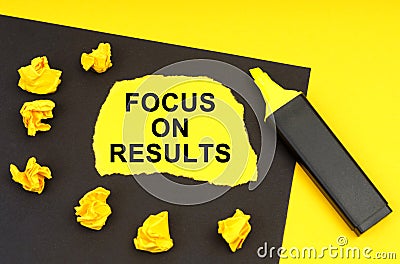 On a yellow background, a black sheet on which lies yellow paper with the inscription - Focus On Results Stock Photo