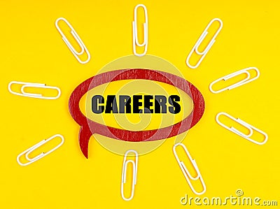 On the yellow surface are paper clips, and a plate inside which the inscription - Careers Stock Photo