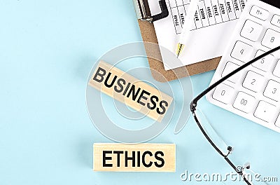 BUSINESS ETHICS text written on wooden block with clipboard ,eye glasses and calculator Business concept Stock Photo