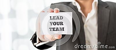 Business executive holding up a white card with a Lead your team Stock Photo