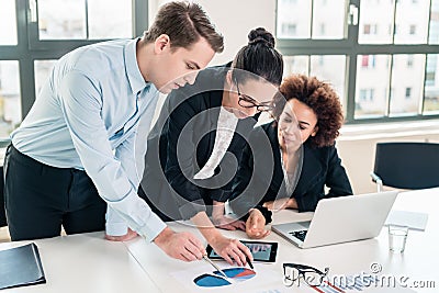 Business experts interpreting pie chart printed on paper Stock Photo