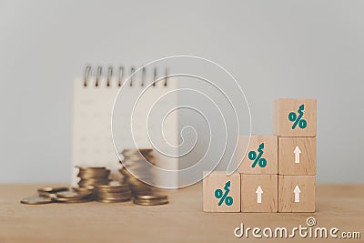 Business and finance concept increasing percentage on wooden cube block and blurred stack of coins and white calendar Stock Photo