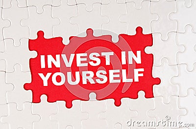 In the middle of the puzzles on a red background it is written - INVEST IN YOURSELF Stock Photo