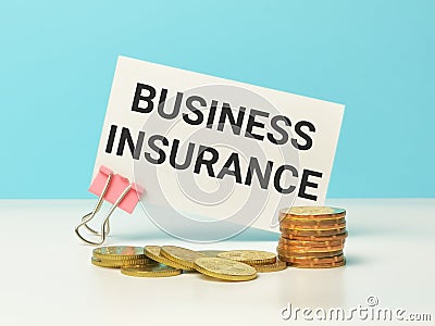 Phrase BUSINESS INSURANCE written on white card with coins. Stock Photo