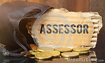 On the table is a bag of money from which sticks out cardboard with the inscription - ASSESSOR Stock Photo