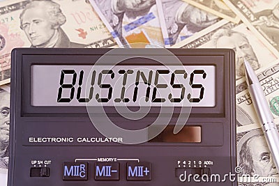 On the table are dollars and a calculator on the electronic board which says BUSINESS Stock Photo