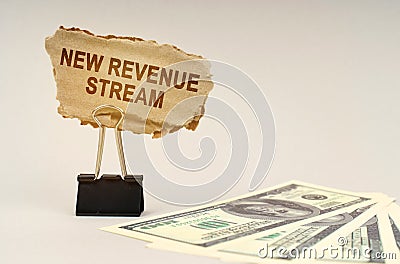 There is money on the table, next to it is a cardboard sign with the inscription - New Revenue Stream Stock Photo