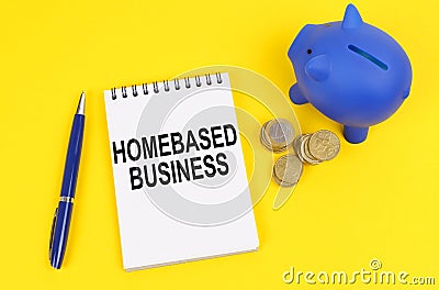 On a yellow surface, a piggy bank, coins and a notepad with the inscription - Homebased business Stock Photo
