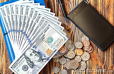 Business Finance and save Money concept. American hundred dollar bills, coins, phone, pen and notebook closeup Stock Photo