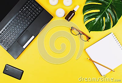 Business flatlay with laptop, mobile phone, glasses, philodendron leaf, candles, cream, pen and notebook. Stock Photo
