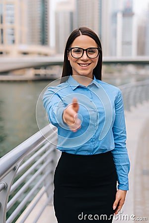 Business, gesture and education concept. Young friendly young smiling businesswoman with opened hand ready for handshake outdoors Stock Photo