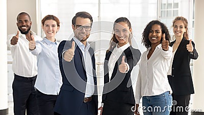 Business leaders with employees showing thumbs up looking at camera Stock Photo