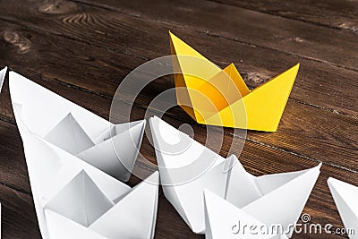 Business leadership concept with white and color paper boats on wooden table Stock Photo