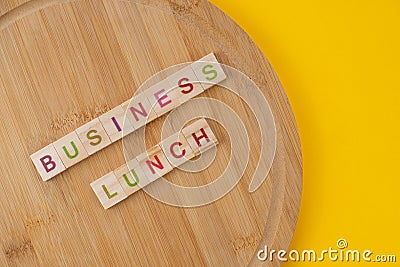 Business lunch menu concept. Scrabble letter tiles on wooden table. Yellow background Stock Photo