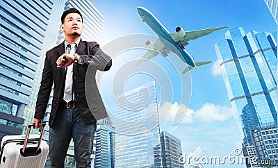 business man and belonging luggage watching to sky and hand watch against high building skyscrapers and passenger plane flying ab Stock Photo