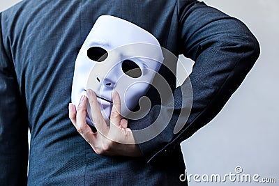 Business man carrying white mask to his body indicating Business fraud and faking business partnership Stock Photo