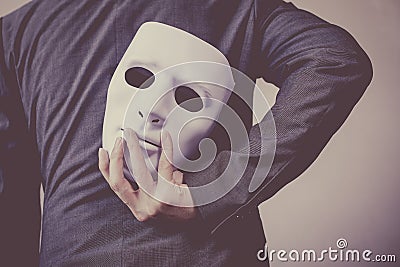 Business man carrying white mask to his body indicating Business fraud and faking business partnership Stock Photo