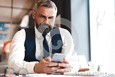 Business man in formal clothing using mobile phone. Serious businessman using smartphone at work Stock Photo