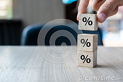 Business man Hand putting wood cube block with percentage symbol icon. Interest rate, financial, ranking and mortgage rates Stock Photo