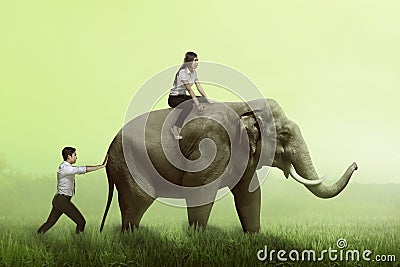 Business man help pushing elephant while his friend sit on it Stock Photo