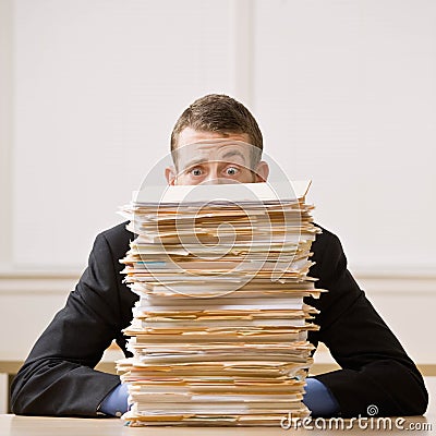 Business man hiding behind tall stack of folders Stock Photo