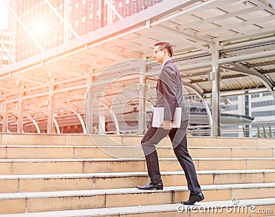 Business man with his laptop going up the stairs in a rush hour to work . Hurry time Stock Photo