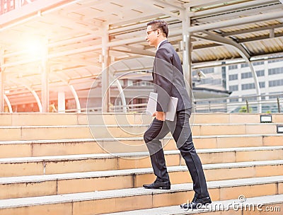 Business man with his laptop going up the stairs in a rush hour to work . Hurry time Stock Photo