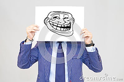 Business man hoding card with troll face on grey background Stock Photo