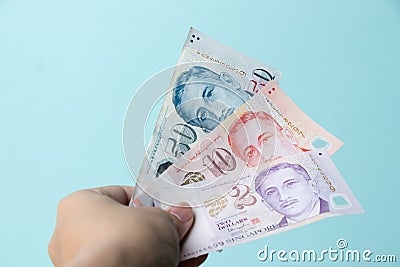 Business man hold 2, 10, 50 Singapore dollar bank note on blue background Stock Photo