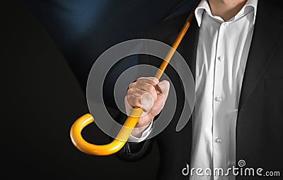 Business man holding umbrella with wooden handle on his shoulder Stock Photo