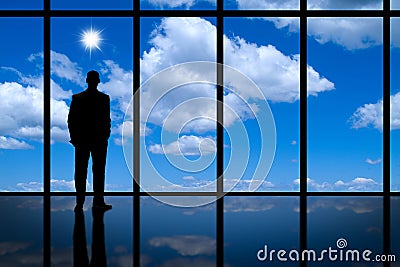 Business Man looking out of high rise office window at blue sky bright sunshine and white clouds. Stock Photo