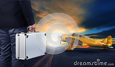 business man with metal strong luggage standing in airport runways with yellow old yellow propeller plane use for air transport Stock Photo