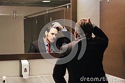 Worried Hispanic Business Man Looking At Hairline In Office Restrooms Stock Photo