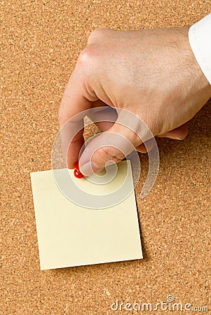 Business man pinning empty yellow sticky paper memo note on cork board Stock Photo