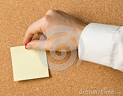 Business man pinning empty yellow sticky paper memo note on cork board Stock Photo