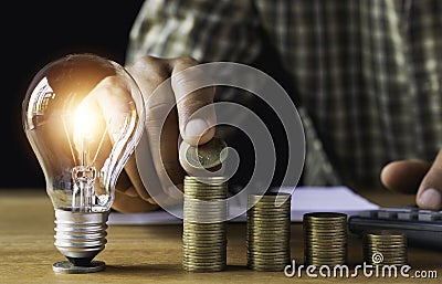 Business man putting coin with light bulb on table for saving bank and account for his money all in finance accounting concept Stock Photo