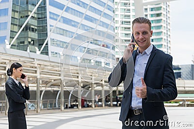 Business man show thumb up and using mobile phone to talk about business plan Stock Photo