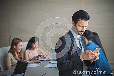 Business man smart and handsome standing using smartphone with team mates working in meeting room at office Stock Photo