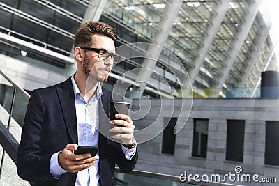 Business man stand at street holding a smartphone and coffee in office park Stock Photo