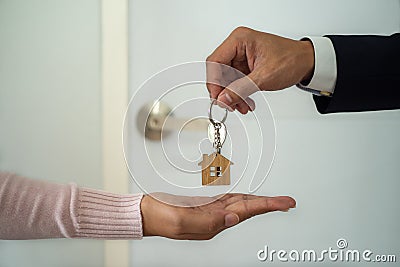 The business man in the suit giving a house key to the woman hand. Stock Photo